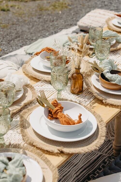 Table set outside with white plates and bowls and brown and green decor