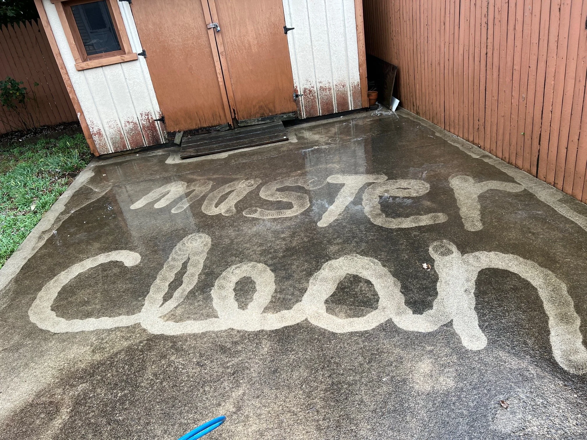 Wet concrete driveway with the phrase 'MUST BE CLEAN' written in the cement.