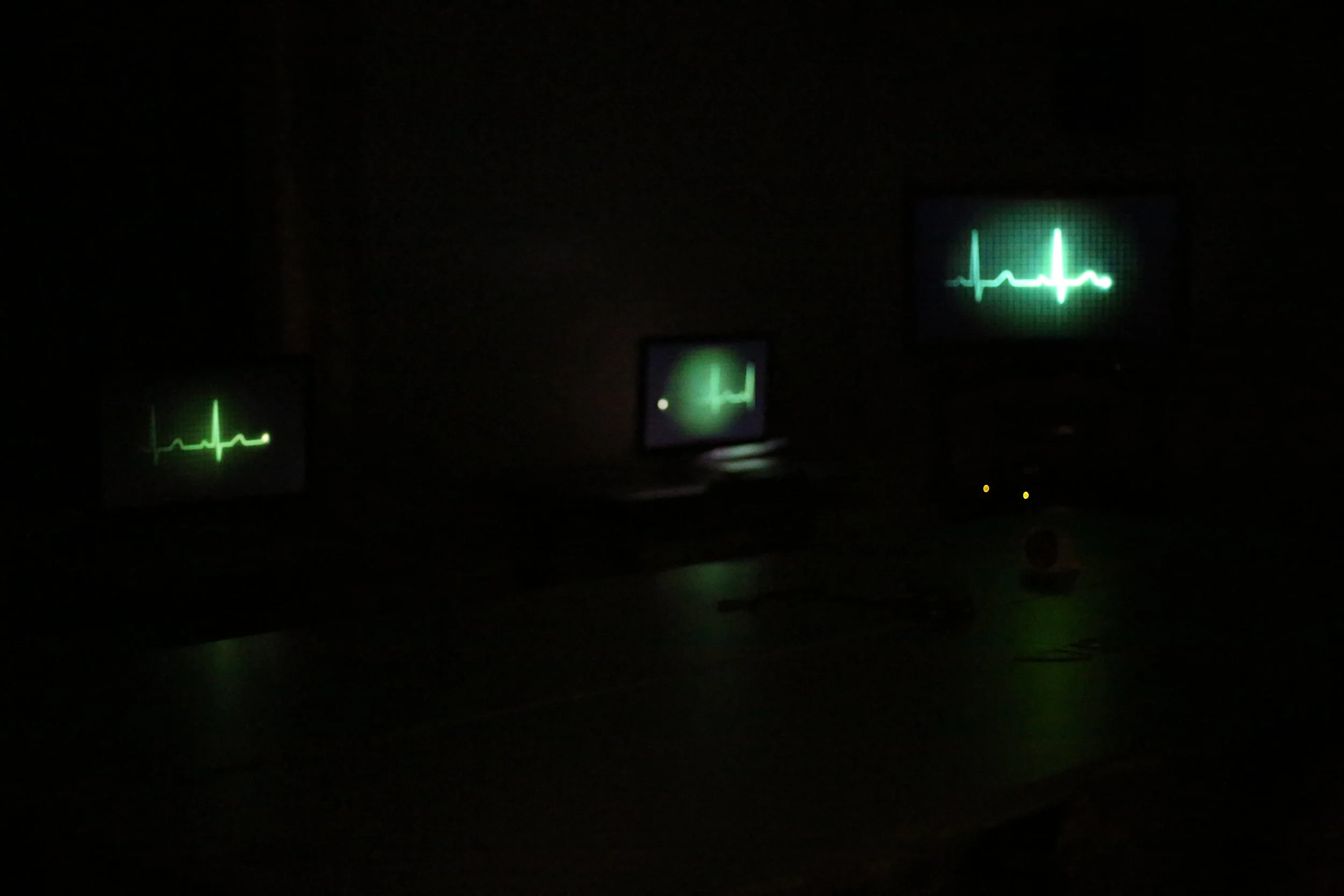 A dark room with three monitors glowing in green