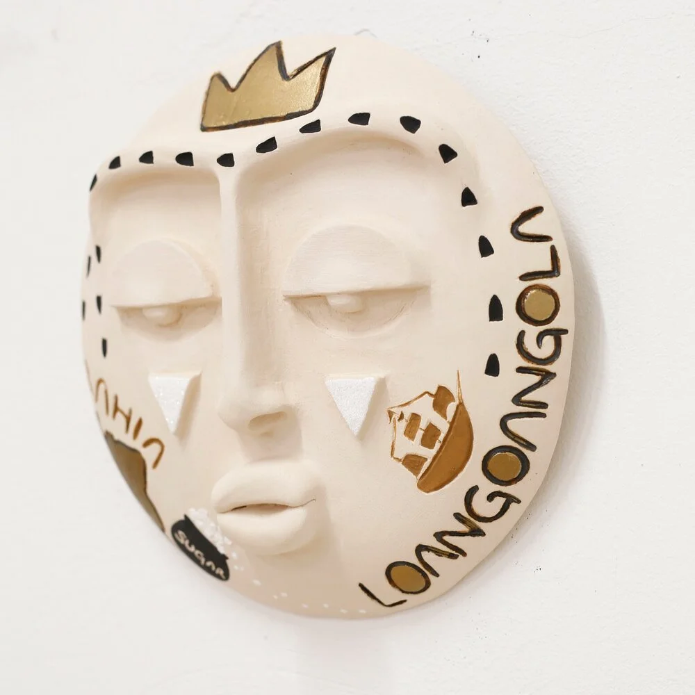 A off-white round mask with half closed eyes and black and gold accents