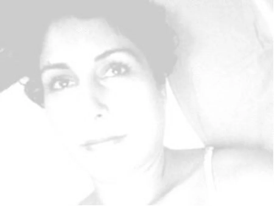 Moni Brar smiles slightly, looking upward at something just out of frame. The image is in a soft grayscale.