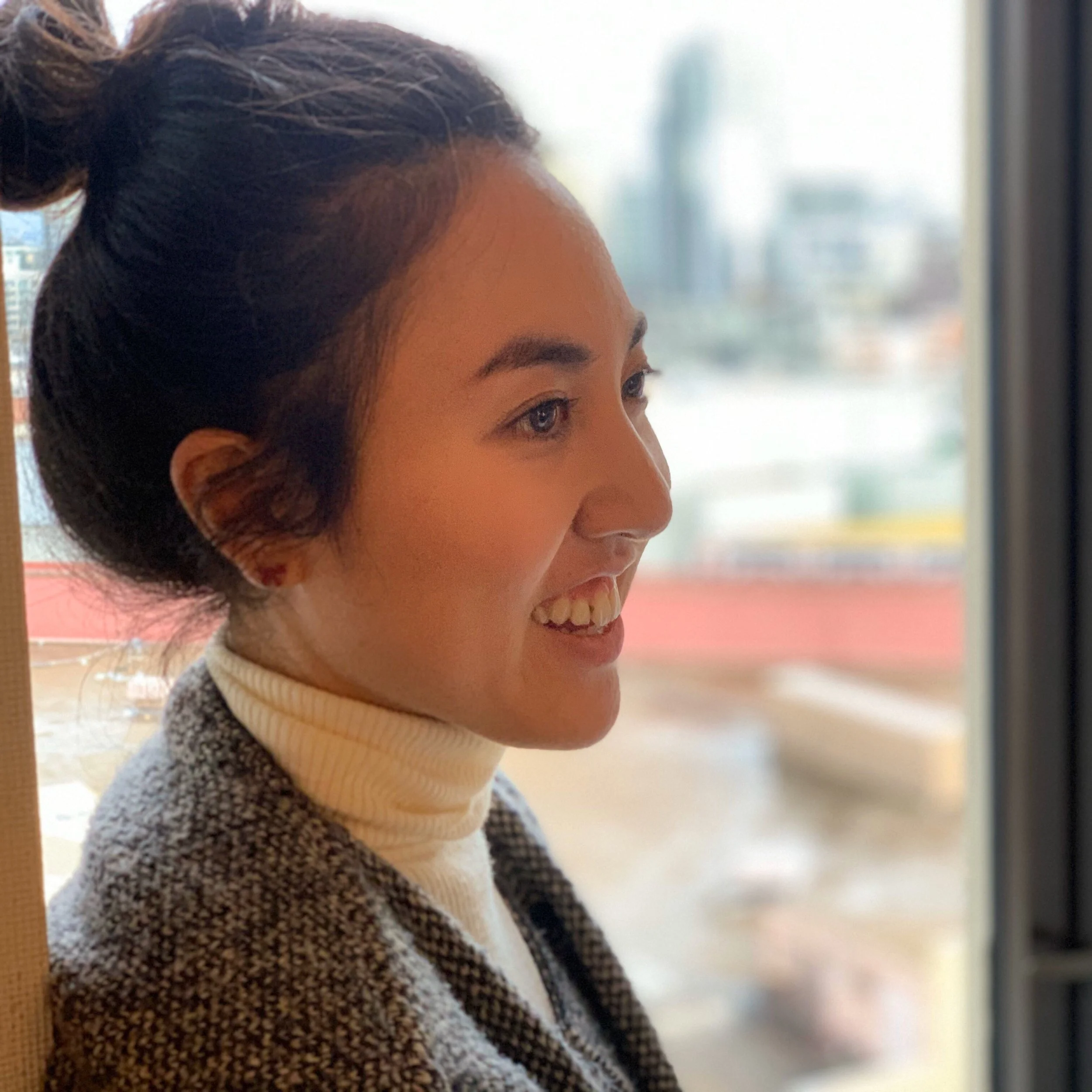 A photo of Akari Komura seen in profile, smiling, with her hair in a bun.