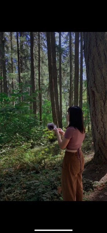 Yvonne in the forest, holding a microphone, capturing the breath of life in stillness.