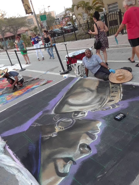 Artist Dalhia Perryman (The Black Dalhia) next to a piece of chalk artwork
