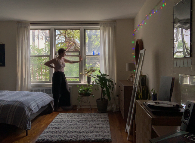 Christiana stands with her arm on the window frame