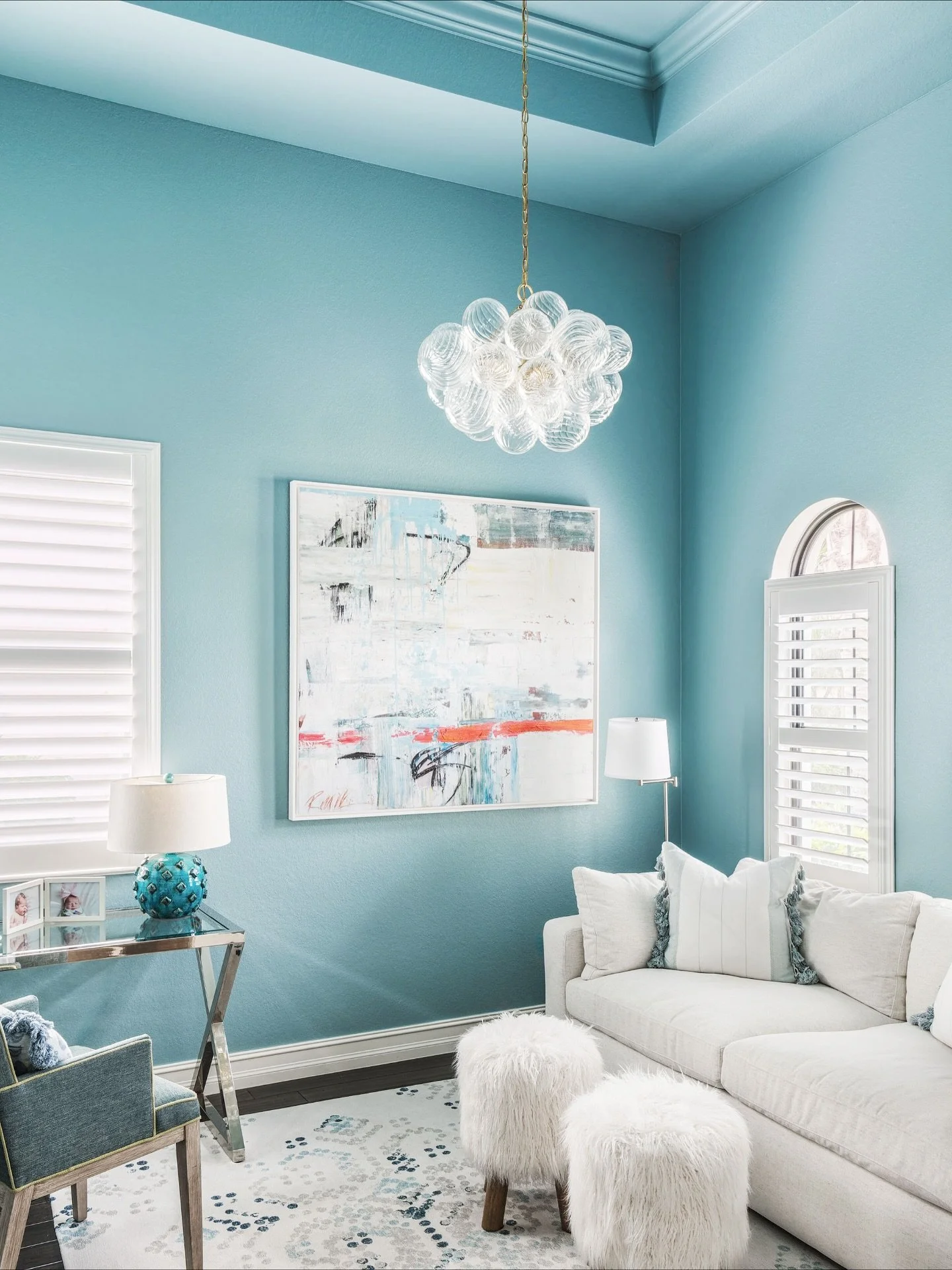In the den of this Naples home, we drew inspiration from the client&rsquo;s artwork to create a dramatic yet calming atmosphere by color-drenching the space. Choosing the right paint was key to the design. We selected a deep aqua hue with a pearl fin