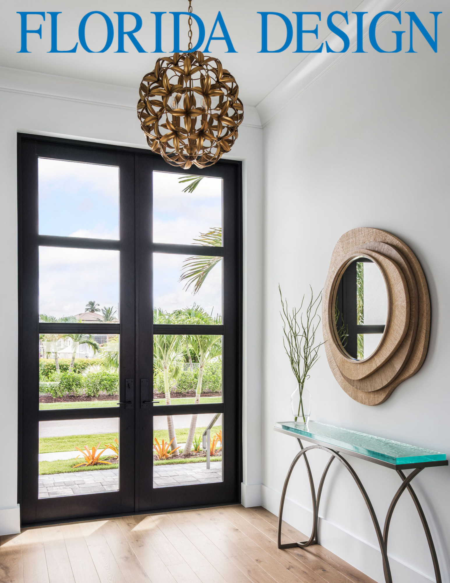 Modern entryway with large glass door, wooden flooring, decorative mirrors, and minimal decor.