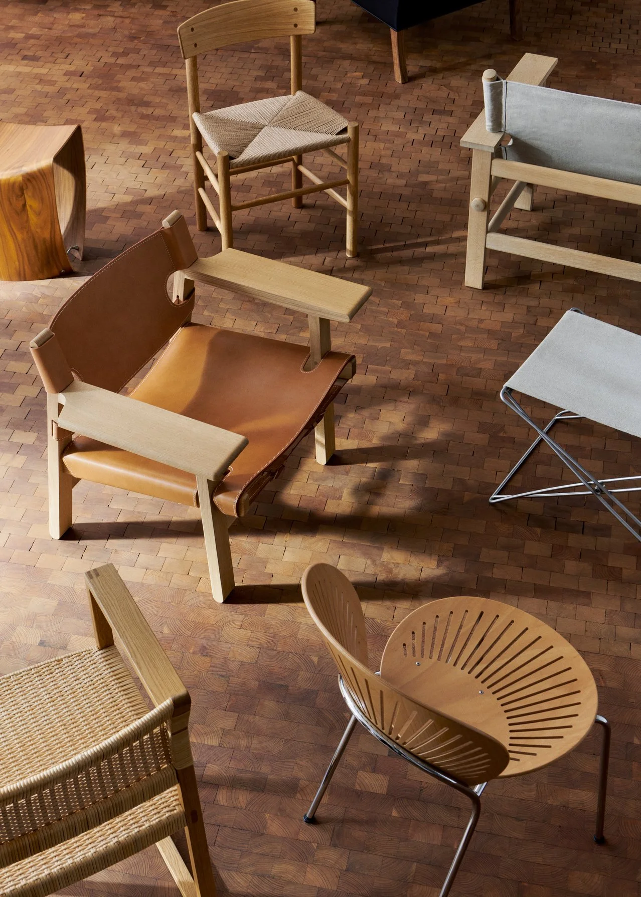 Vari sedie di diversi stili e materiali disposte su un pavimento di legno.