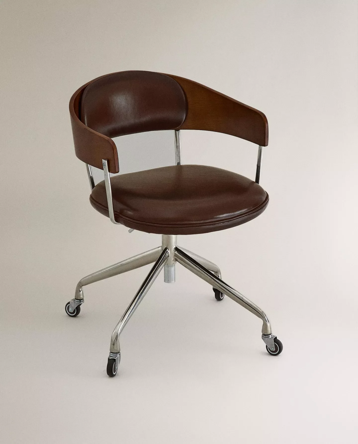 Sedia girevole in stile vintage con rivestimento in pelle marrone e struttura in metallo, sfondo bianco.