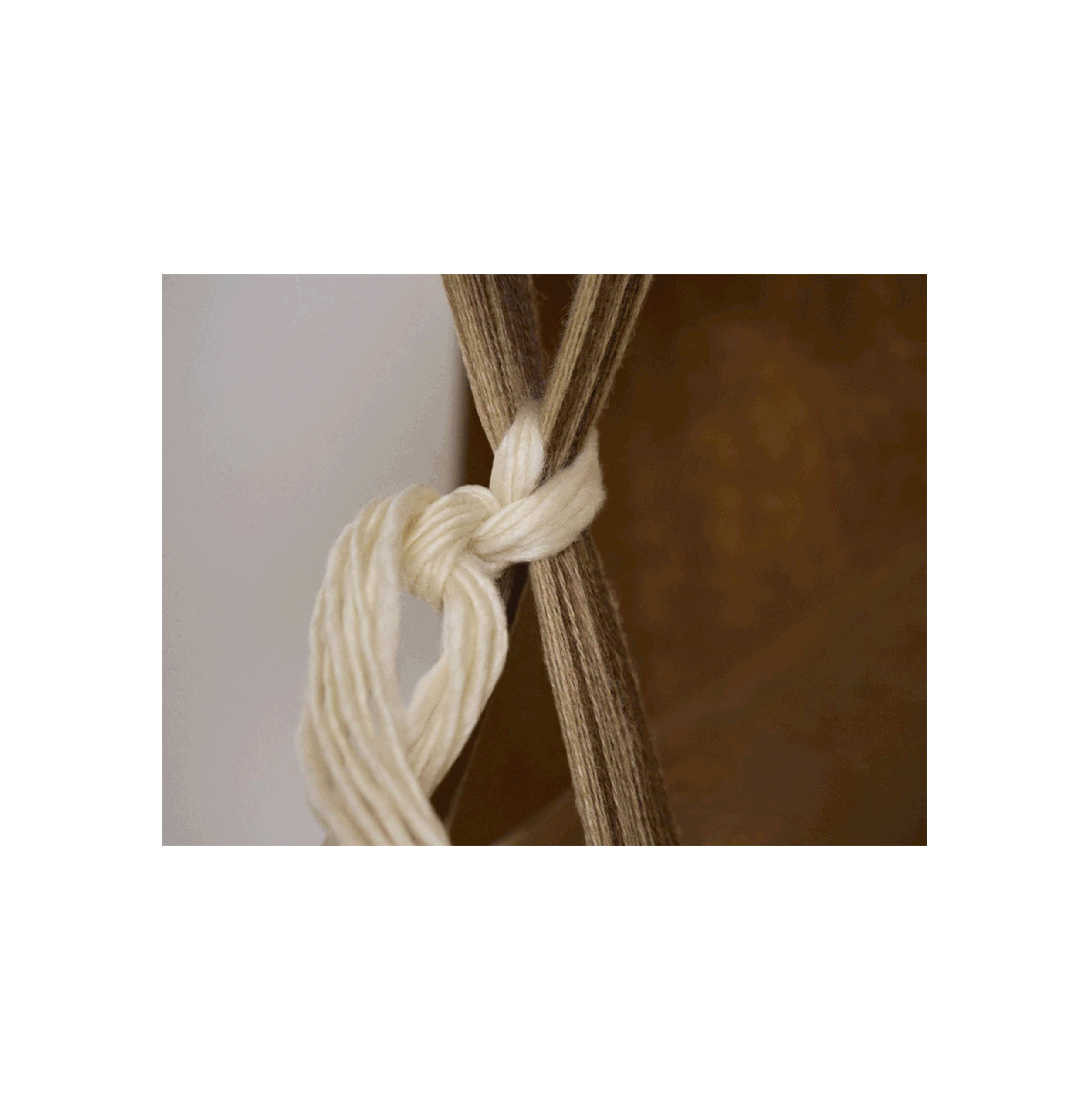 Chiusura di un nodo con corda di cotone di colore beige, attorno a un pezzo di corda di colore marrone.