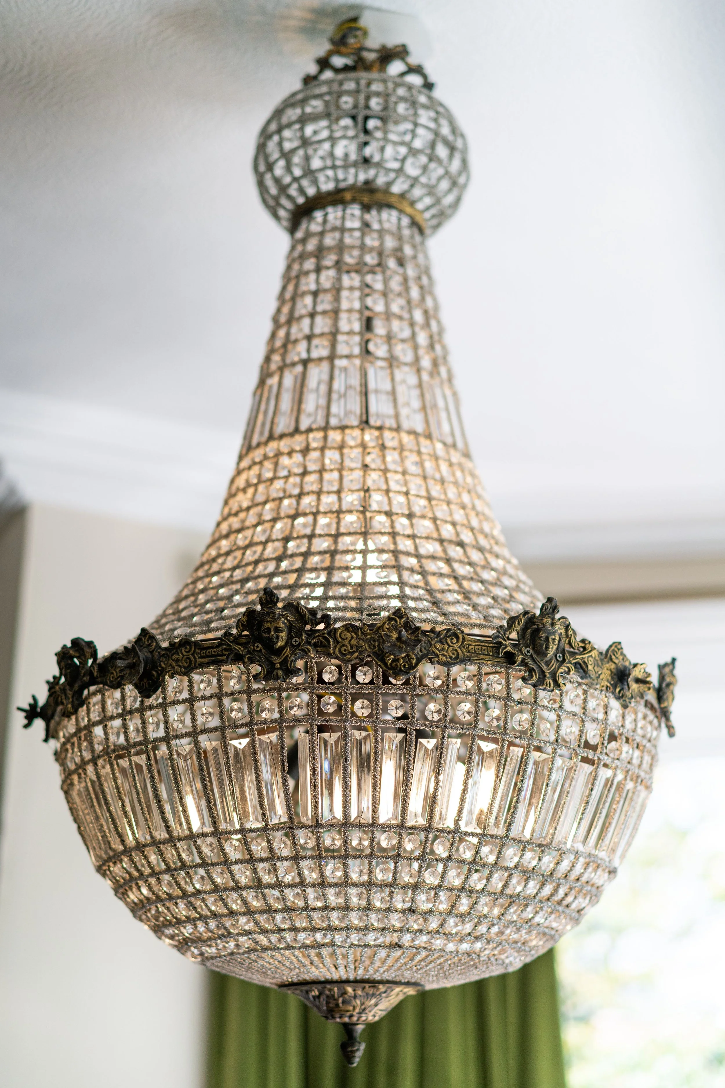 Elegant crystal chandelier with intricate metal detailing hanging from a ceiling.