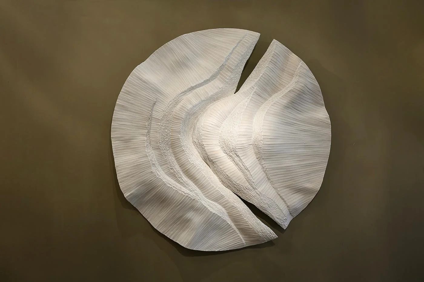 Round white sculptural wall relief split by a flowing curve, handmade by Michel Mullèr