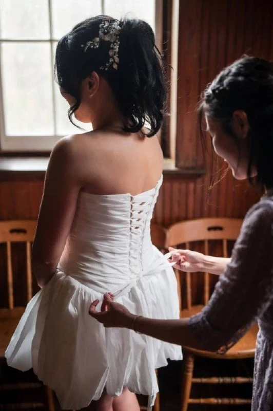 Friend helping a bride into their modern nontraditional dress before intimate queer Korean wedding.