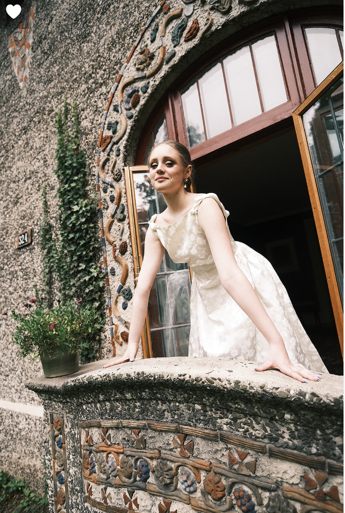 Bride standing on a balcony, wearing a vintage designer wedding gown from Maybelle.