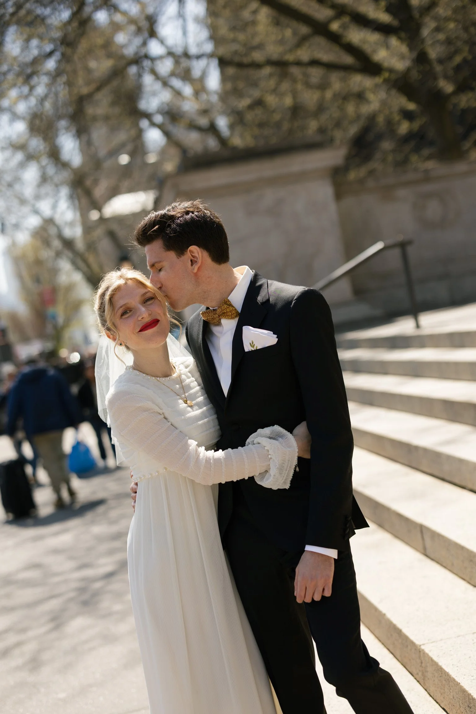 A bride, wearing a vintage chiffon wedding dress, and groom standing near steps in NYC