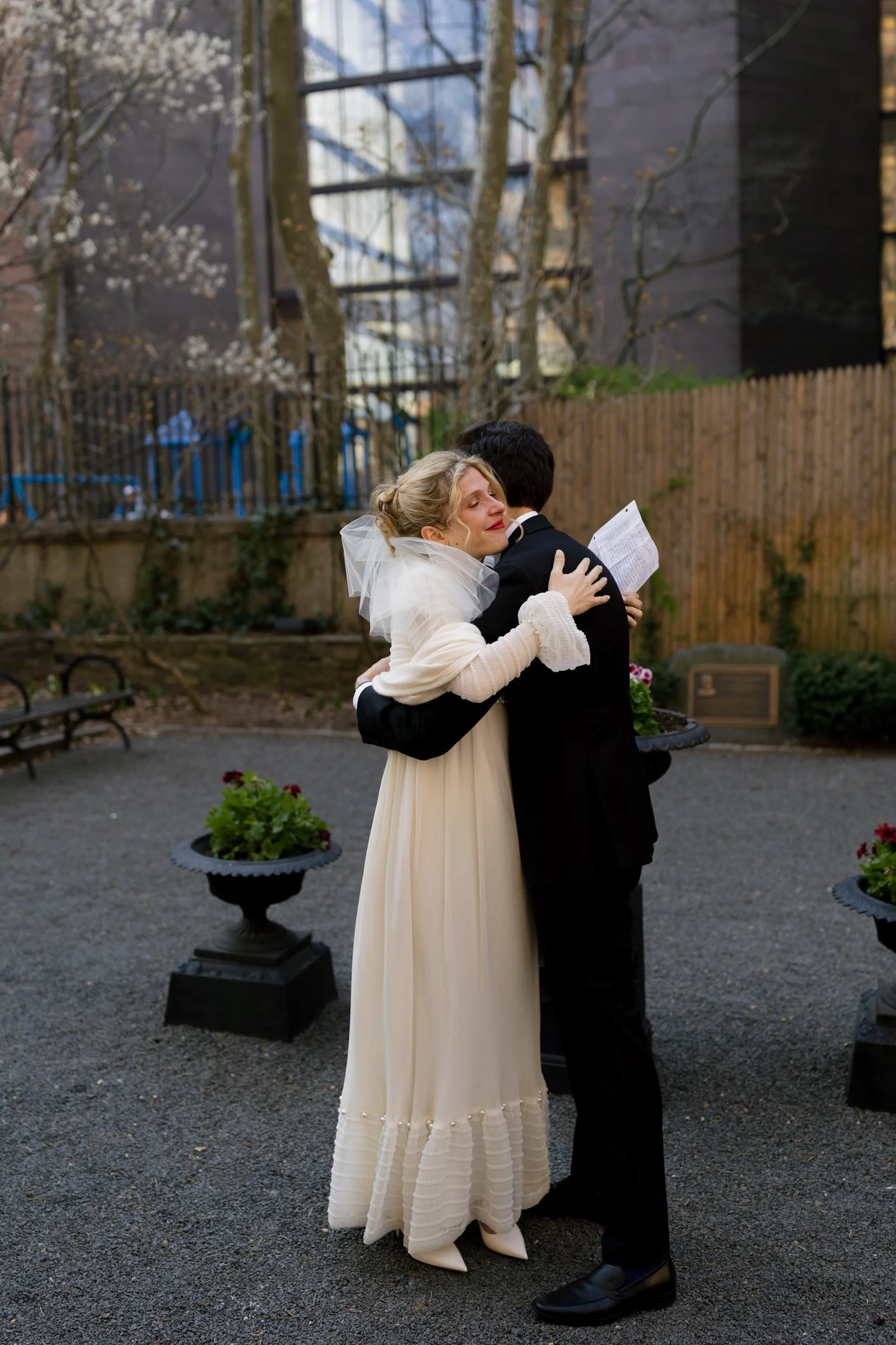 A bride and groom hugging after their vows in an urban NYC park.