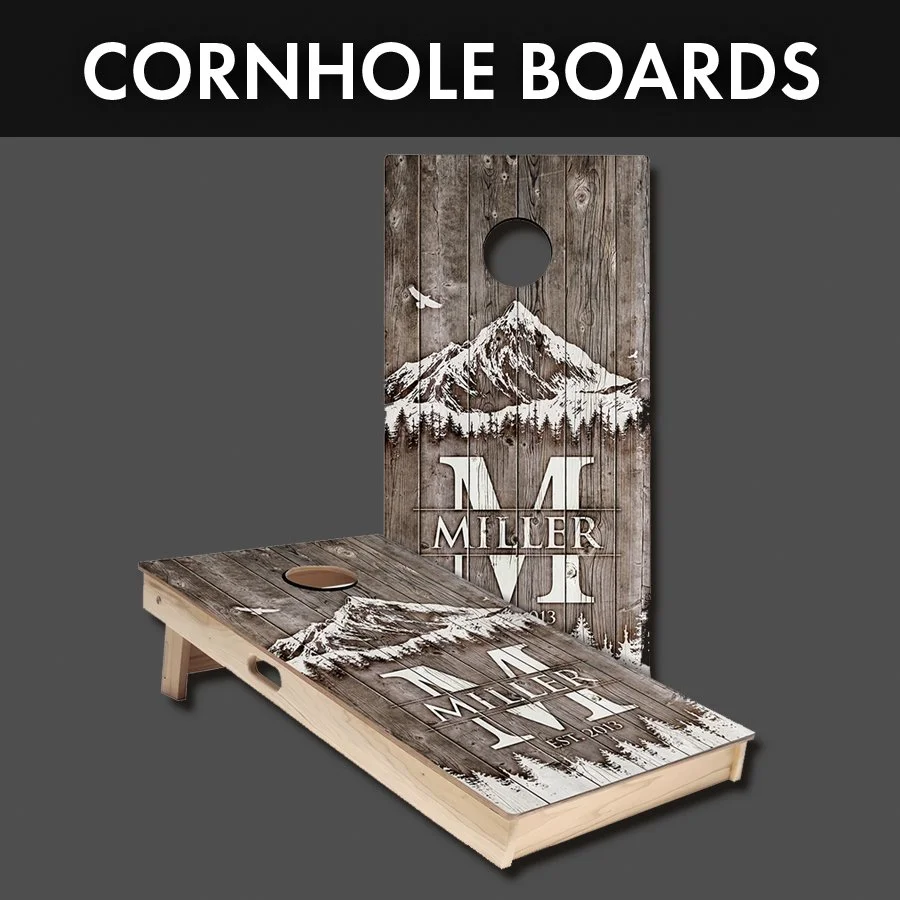 Two custom cornhole boards with mountain and forest design, personalized with the name 'Miller' and the year 2013, featuring a circular hole for gameplay, against a plain background.