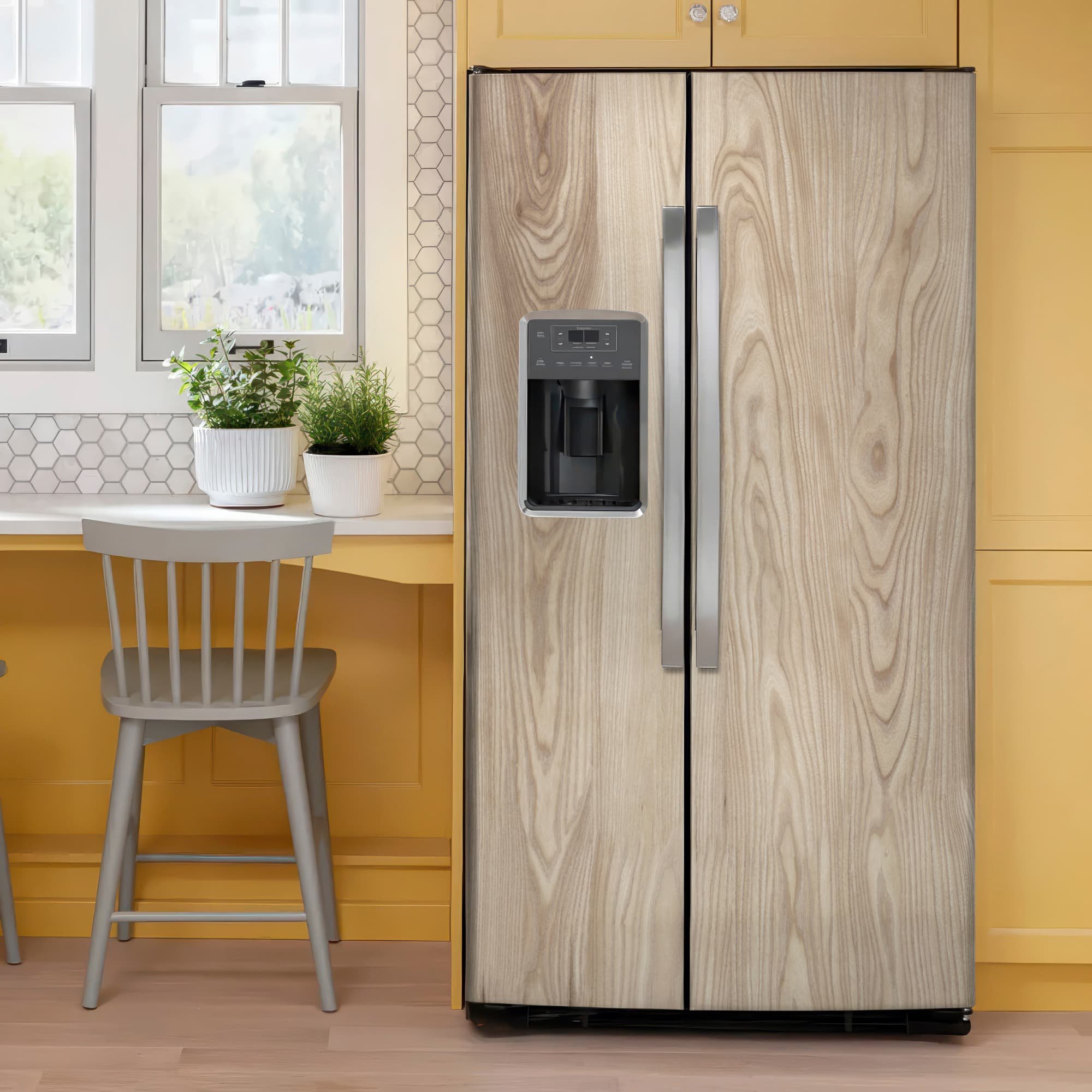 Ash wood vinyl wrap on a side by side refrigerator in a bright kitchen with yellow cabinets