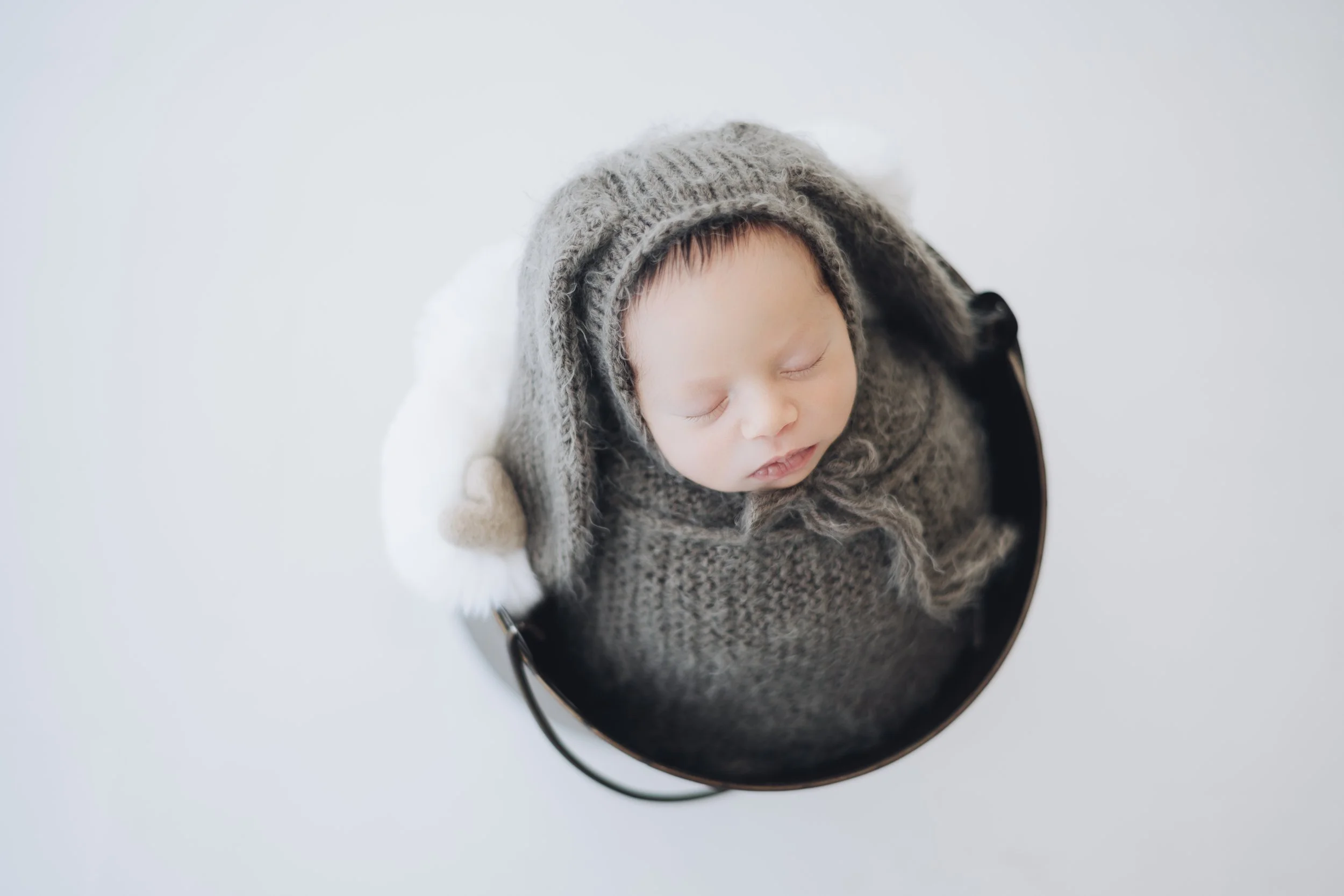 Sleeping baby in a knit hat and sweater, seen from above.