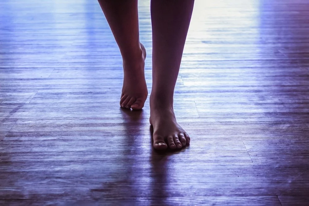 A woman over 55 walking barefoot in the studio building confidence one dance step at a time.