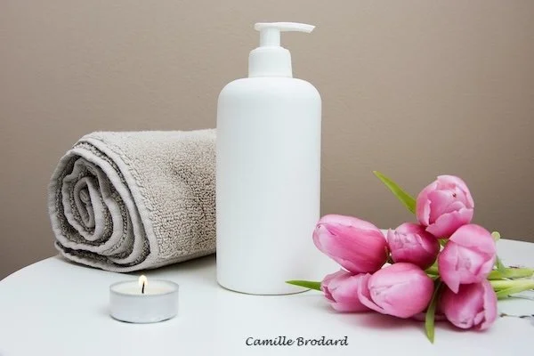 A towel, lotion, tulips and a candle.