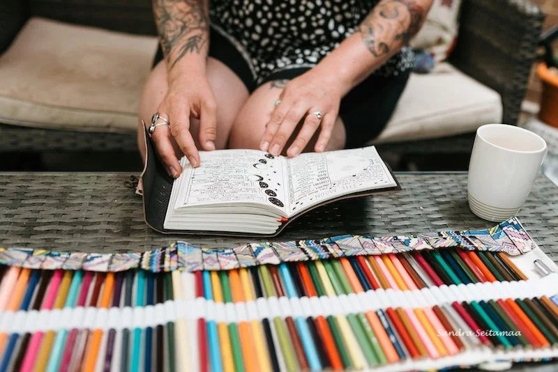 A woman with her journal, coloured pencils and coffee.