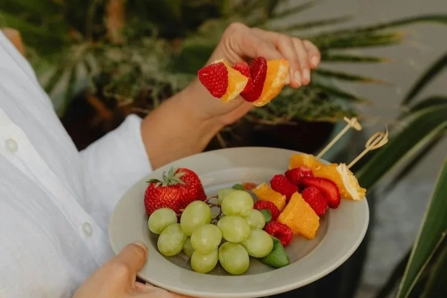 A woman over 55 eating  a variety of fruits  as she practices mindful holiday eating.