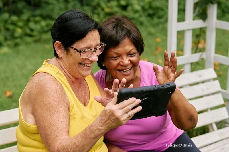 Two women laughing and looking at an ipad.