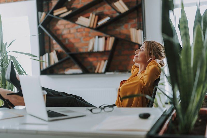 A woman leaning back in her chair at her desk.
