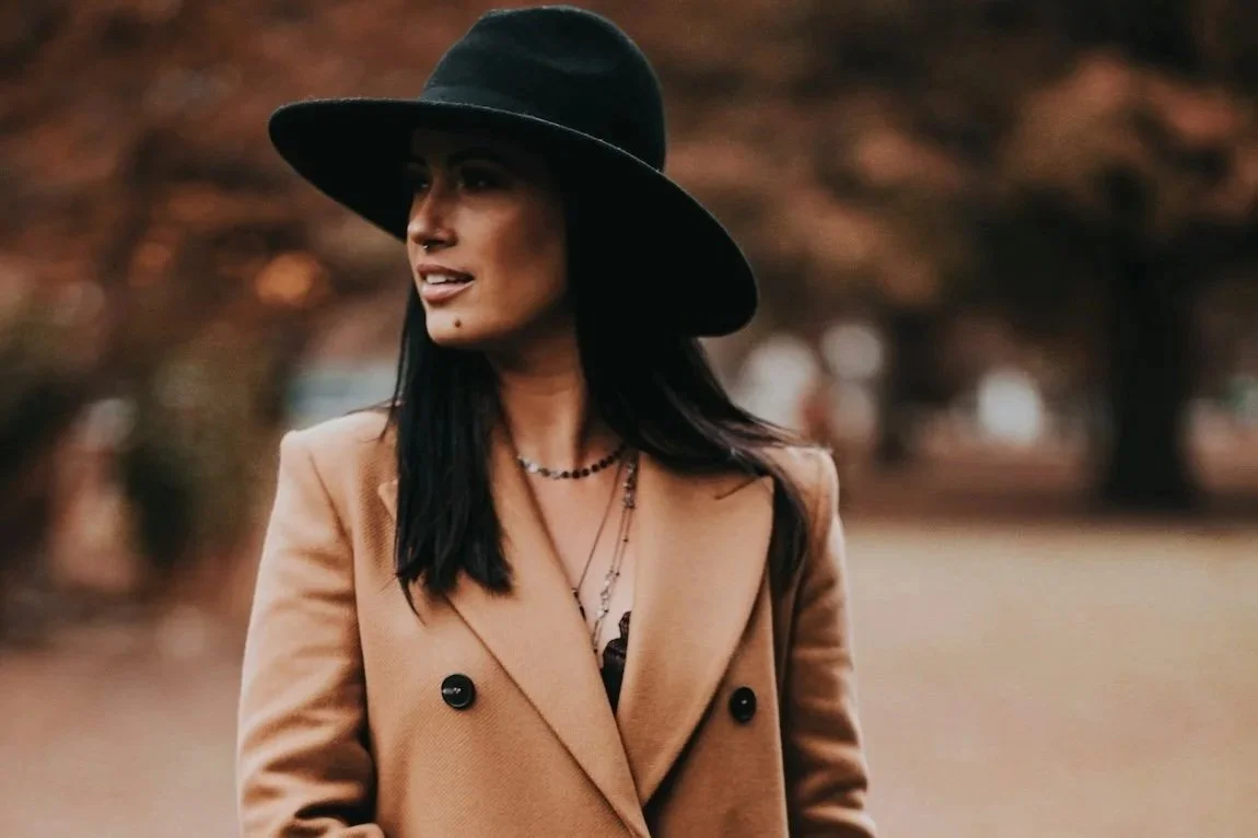 A woman in a stylish hat, coat and purse practicing empowerment strategies.