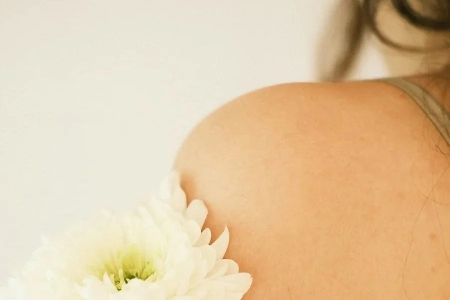 A woman's shoulder and a flower representing spring skincare tips.