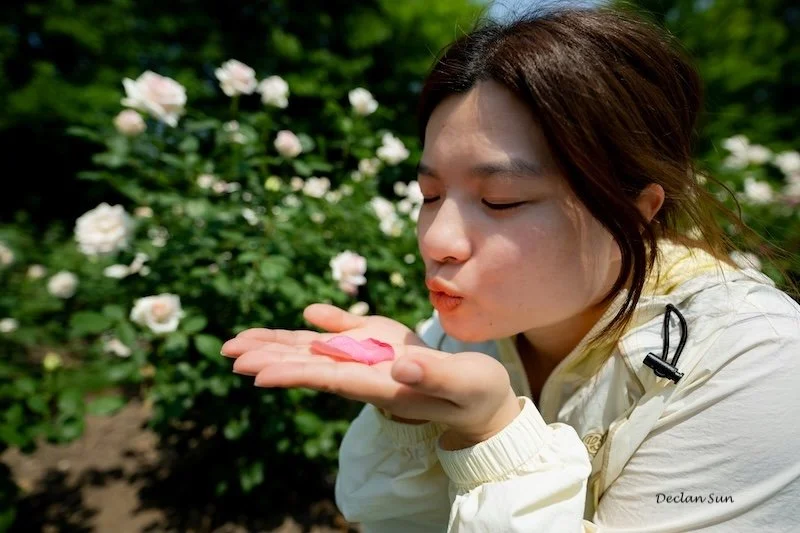 A woman blowing away a flower petal.