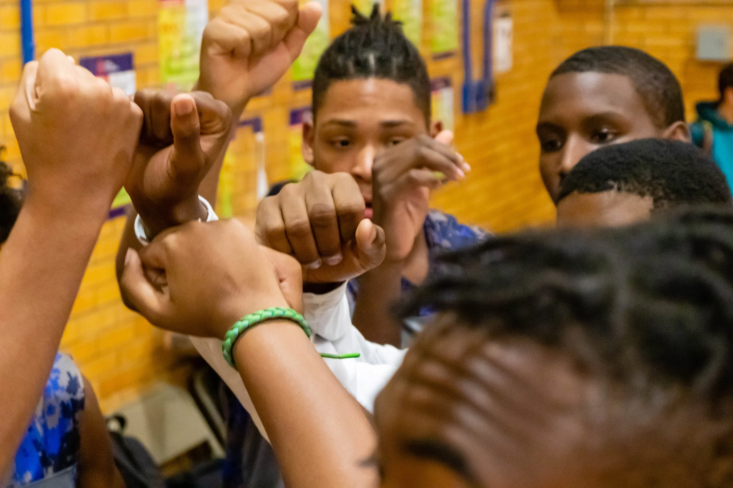 A group of young people engaging in a group arm wrestling activity.