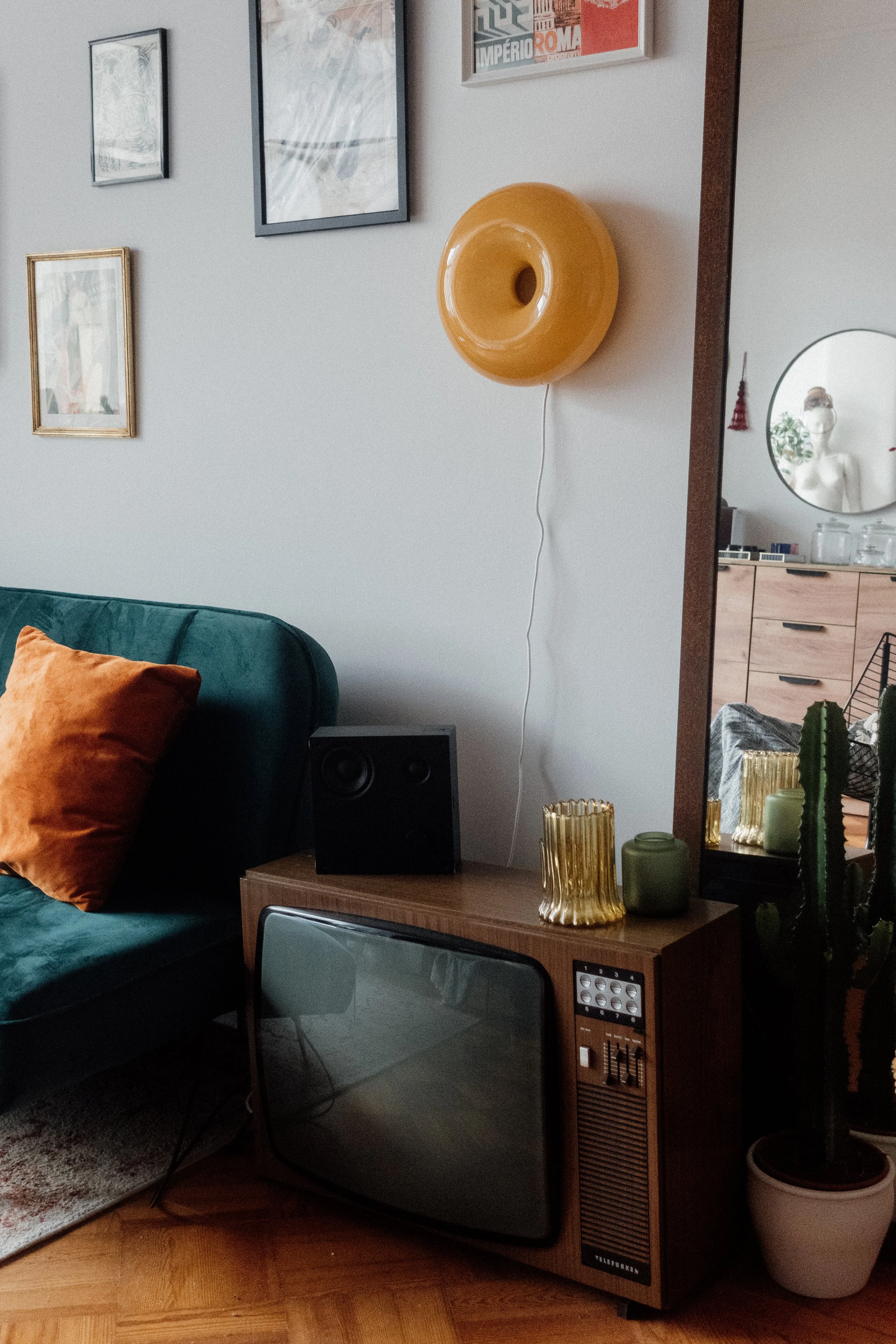 Interior of Akari Photography Studio in Lisbon with green velvet sofa, vintage television, plants, and warm natural light.