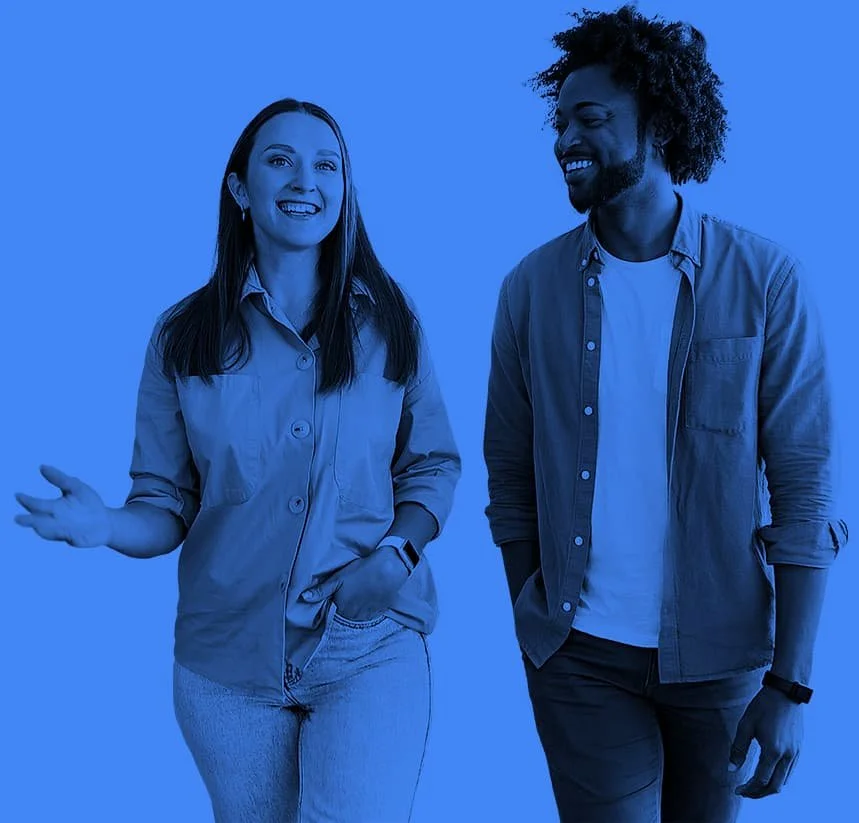 A man and woman smiling and talking casually, standing side by side against a solid blue background.