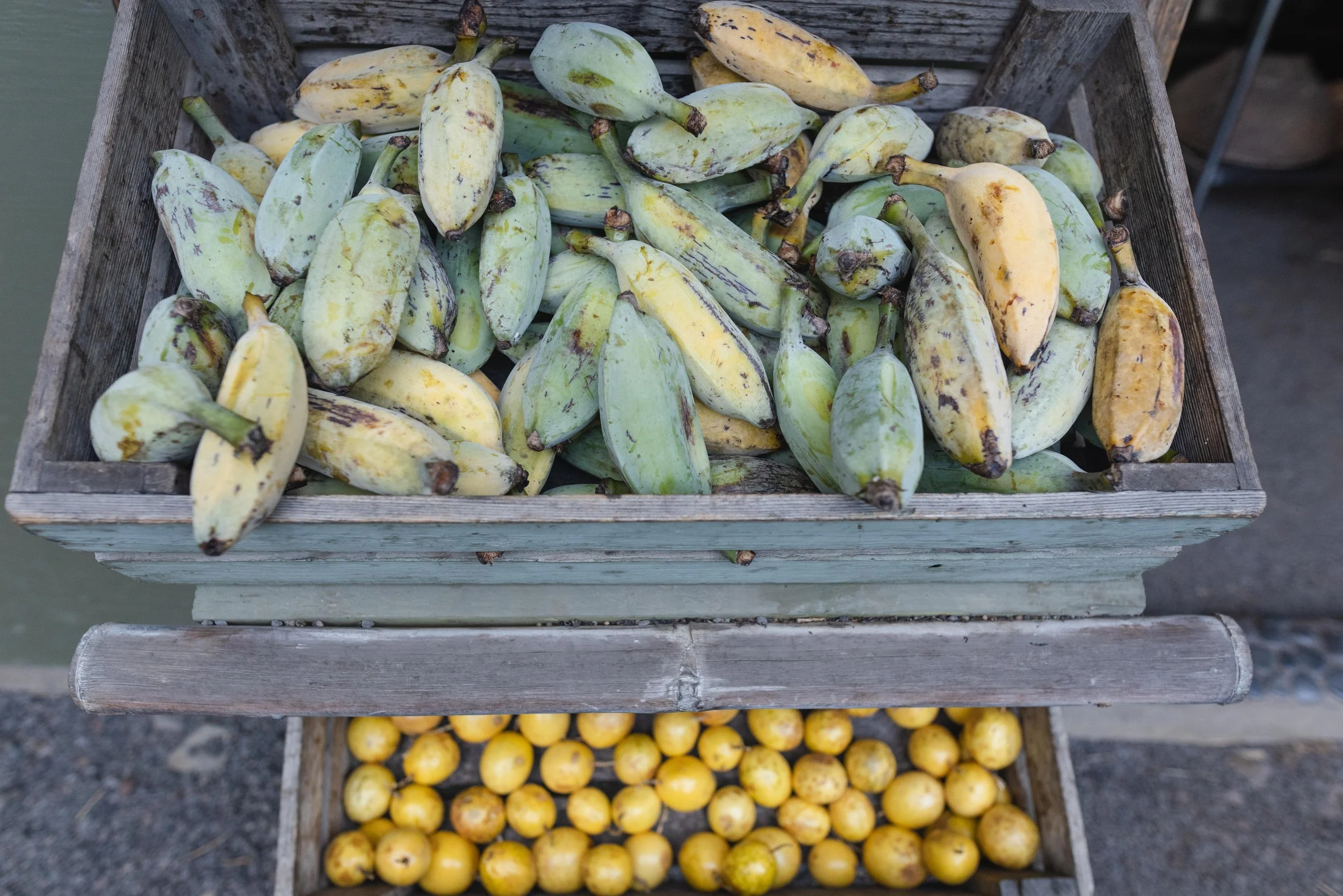 Crates of green and yellow bananas, with other fruits sold at Laulima Farm farm stand on road to Hana, Maui