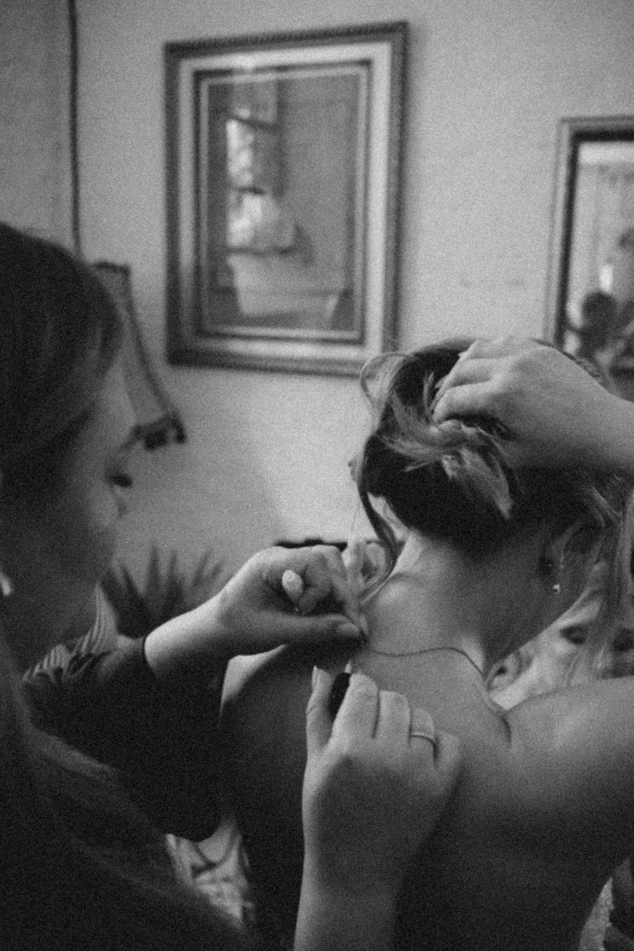 Zwei junge Frauen, die einen Kuss austauschen, in einem Raum mit Kunstwerken an der Wand, in schwarz-weißer Fotografie