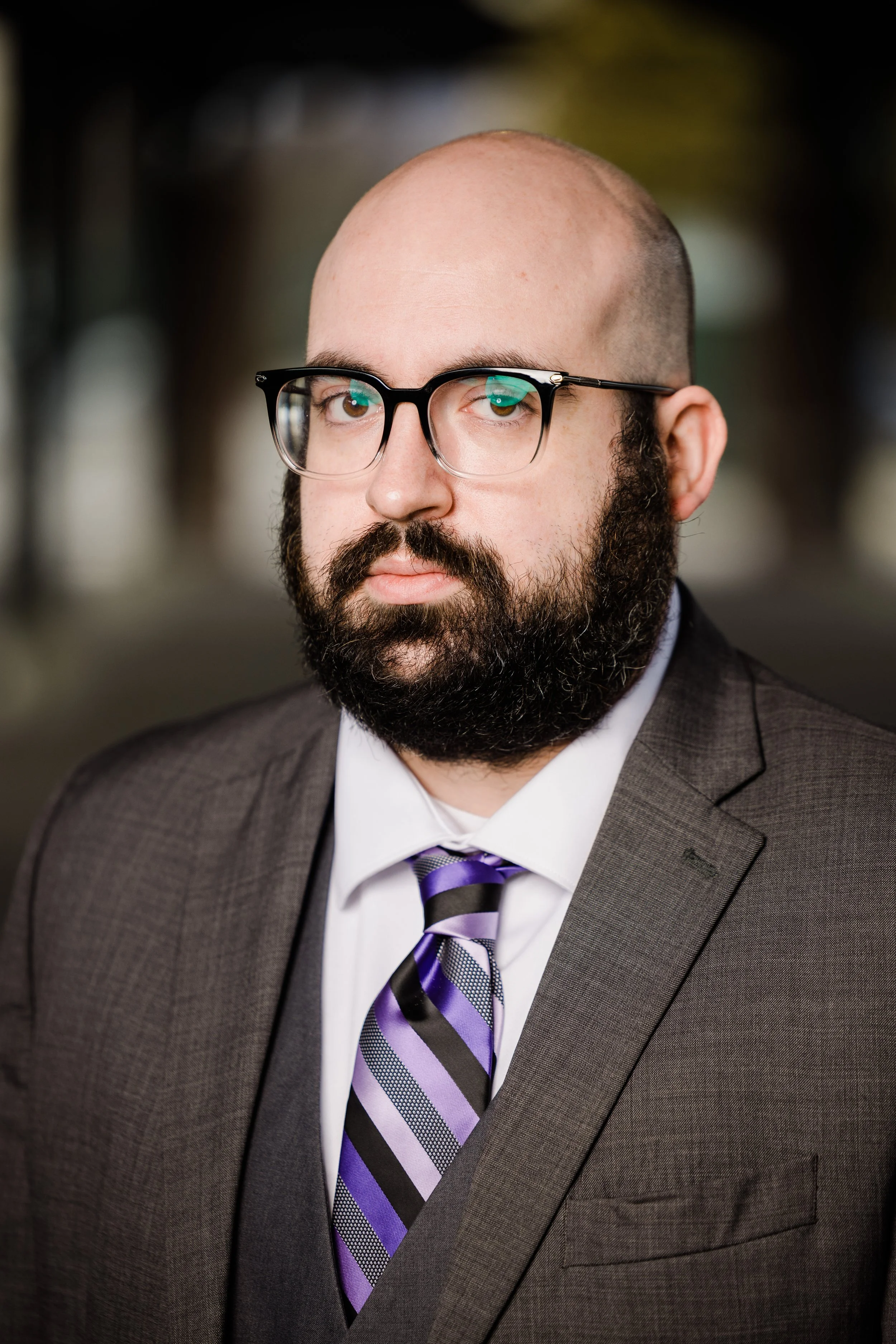 Man with thick beard and mustache wearing a suit and purple striped tie