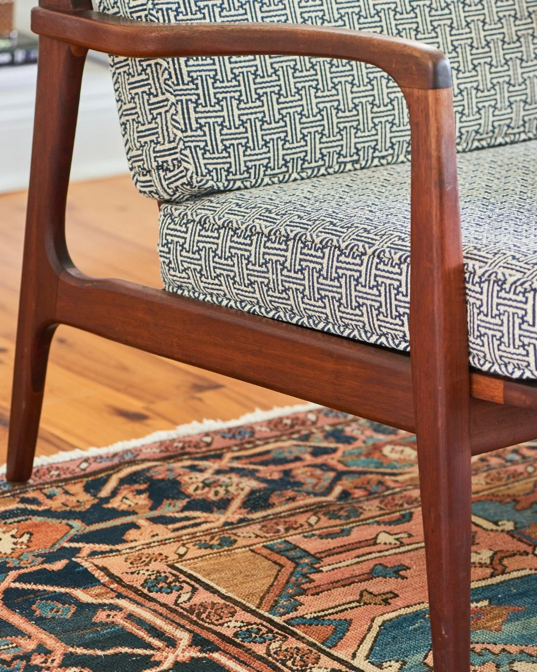 The room that earns its formality.

Coffered ceiling, charcoal velvet sofa, a vintage Persian, doing all the heavy lifting for warmth and history. A glass-and-steel coffee table sits on top of all that pattern without competing. Driftwood, ceramic, o