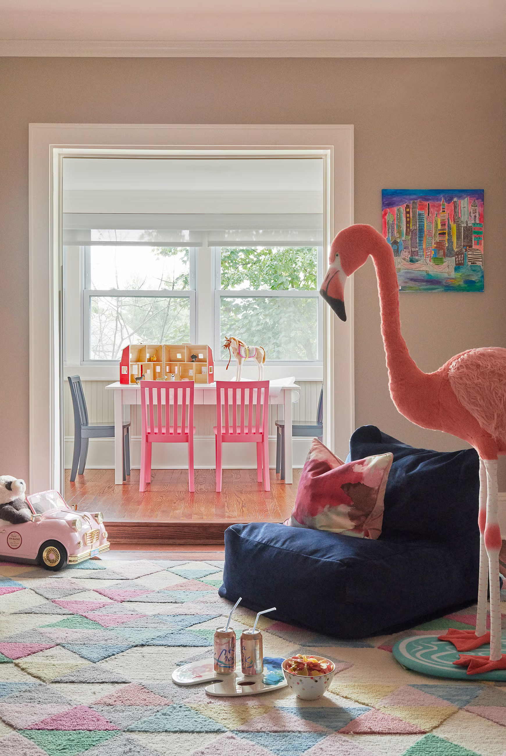 Children’s playroom featuring pink chairs, a creative art table, colorful rug, and playful flamingo décor designed by Georgia Zikas Design.