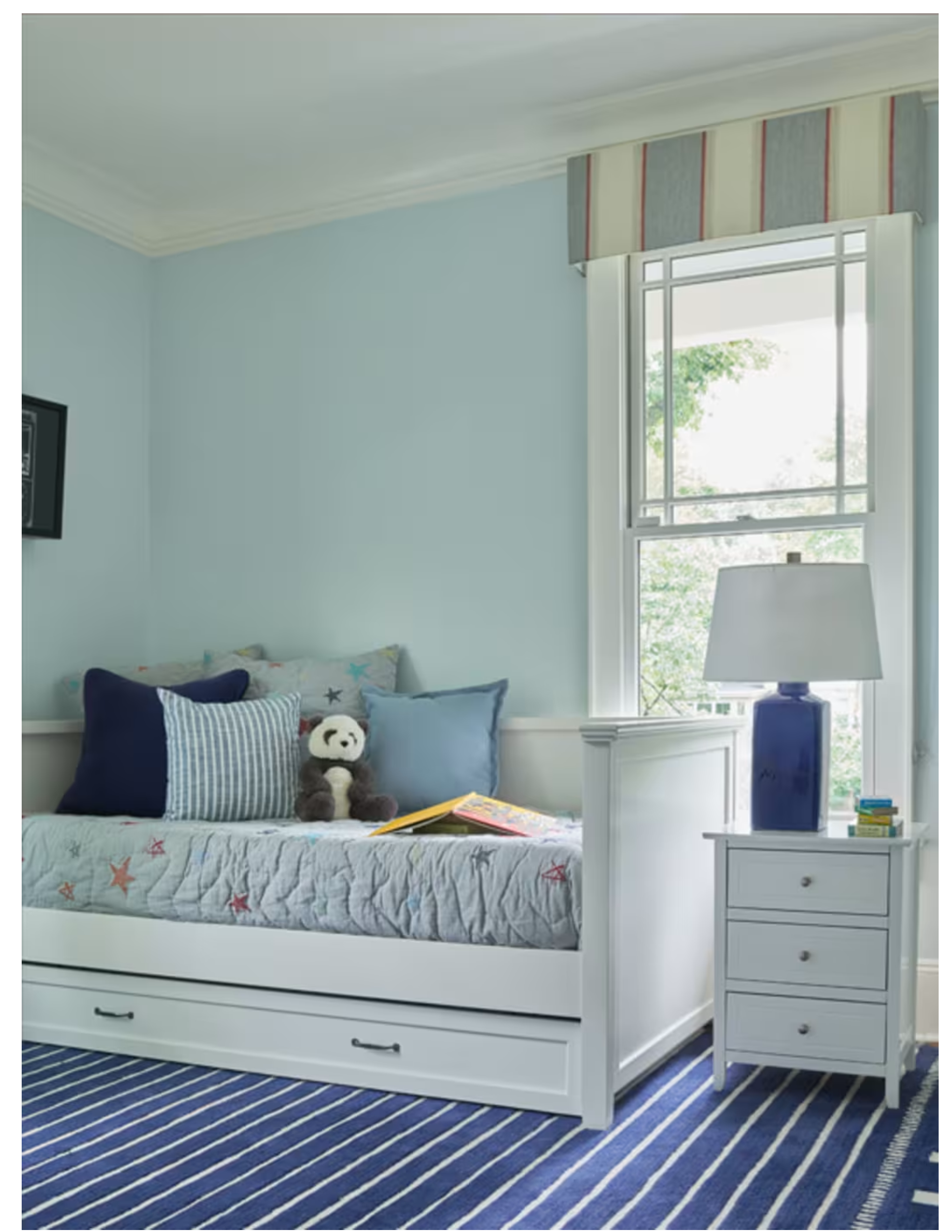 Light blue children’s bedroom designed by Georgia Zikas featuring a daybed, striped rug, and soft coastal-inspired details, as seen in Mansion Global.