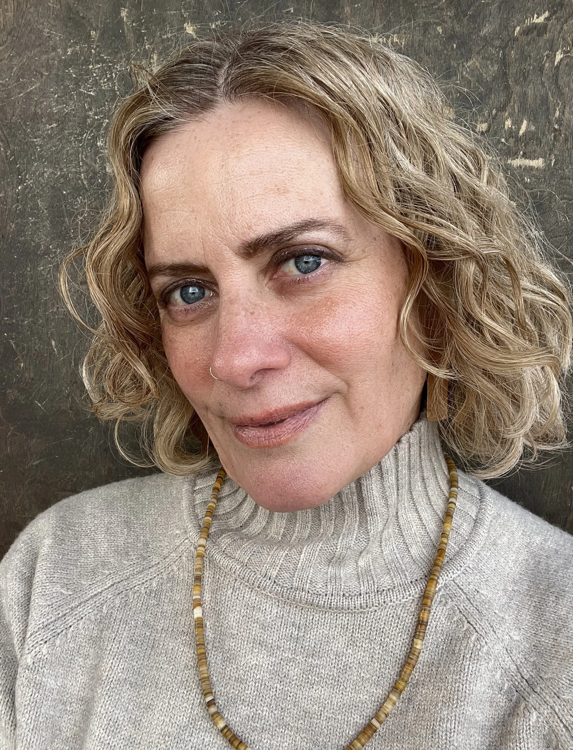 Headshot of Jessie White, founder of Harness Whole Health, wearing a light gray turtleneck sweater and a beaded necklace.