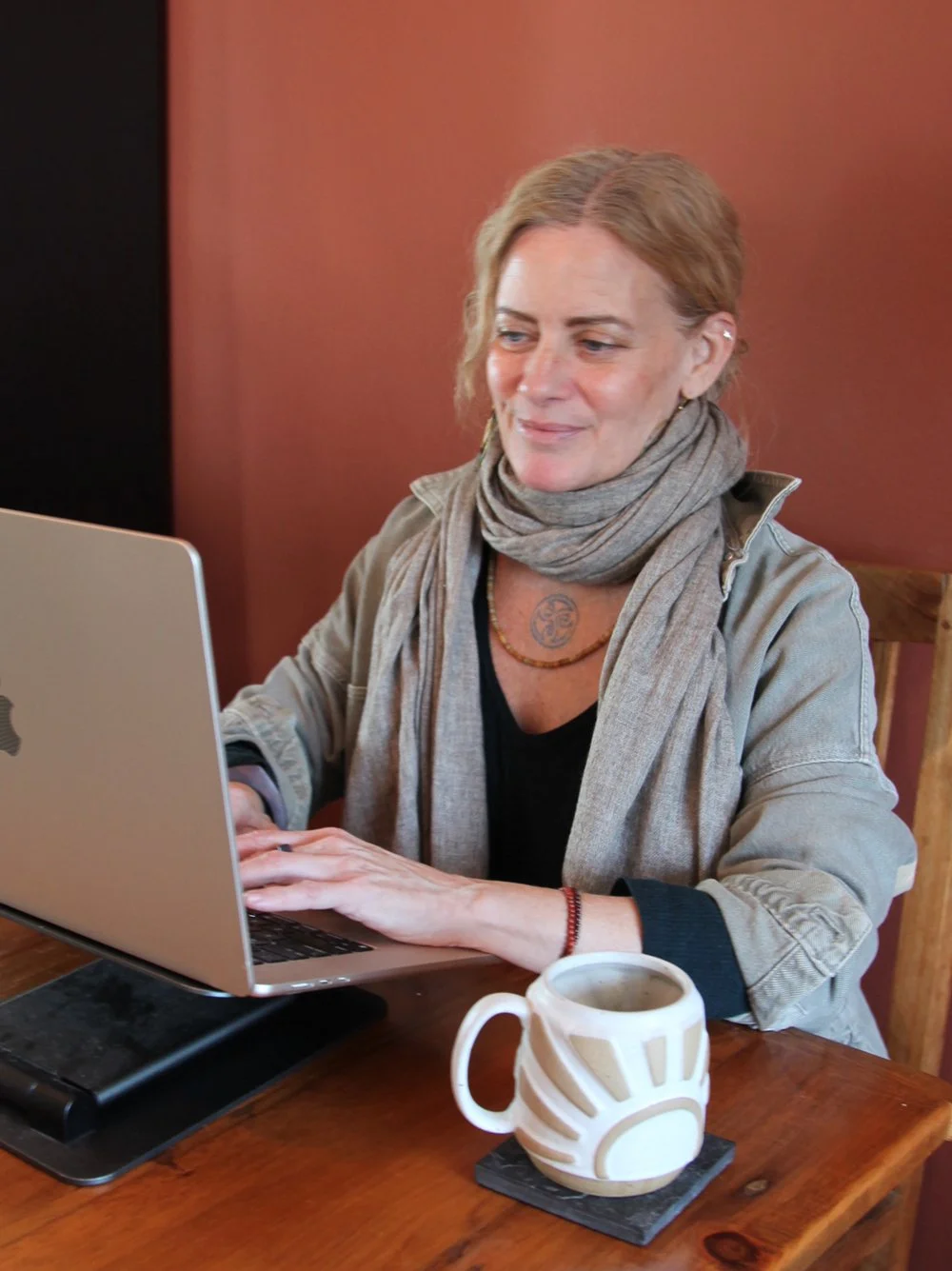 A photo of Jessie White, founder of Harness Whole Health Functional Nutrition, working on a  laptop with a remote client, in a cozy indoor setting.
