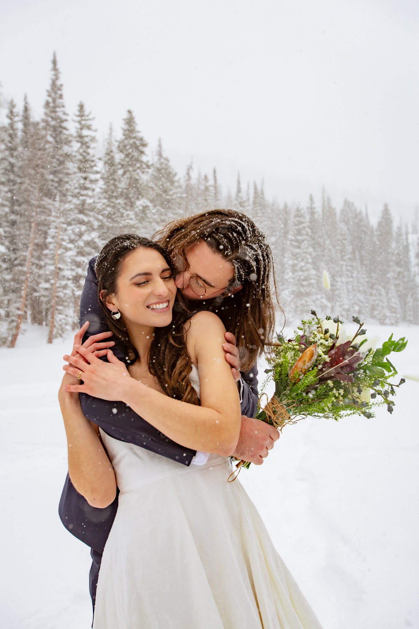 Bride and groom hug tightly after eloping in the middle of a frozen lake at Rocky Mountain National Park 