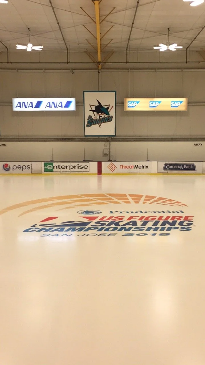 Empty ice hockey rink with branding and advertisements on the ice and walls, including logos for Purdue, Visa, San Jose Sharks, ANA, SAP, Pepsi, Enterprise, ThreatMetrix, and Comerica Bank.