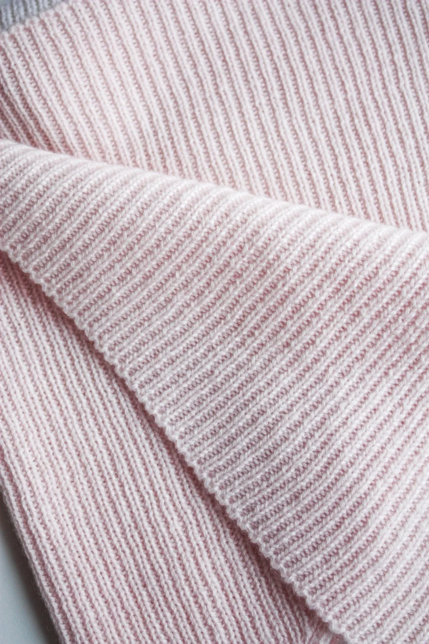 Gros plan d'un tissu en maille rose et blanc avec texture rayée.