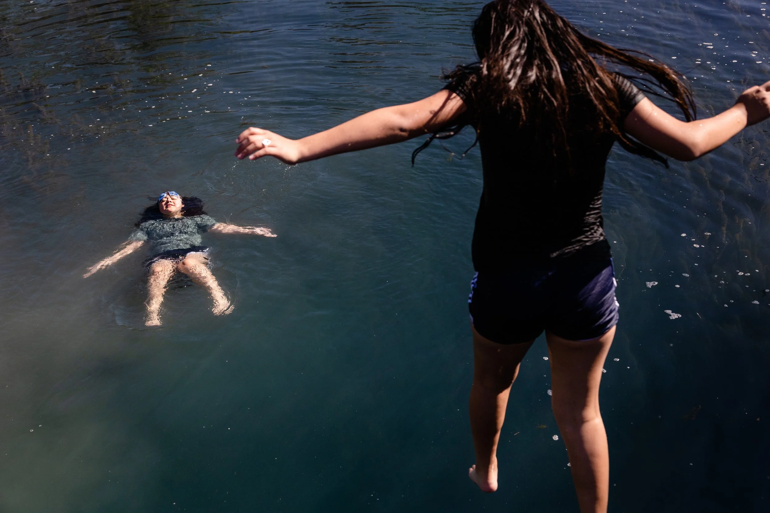  Illiaña Treviño floats in the water, as her sister Ameliaña jumps from a suspension bridge at the San Felipe Natural Spring Park in Del Rio on March 25, 2023. 