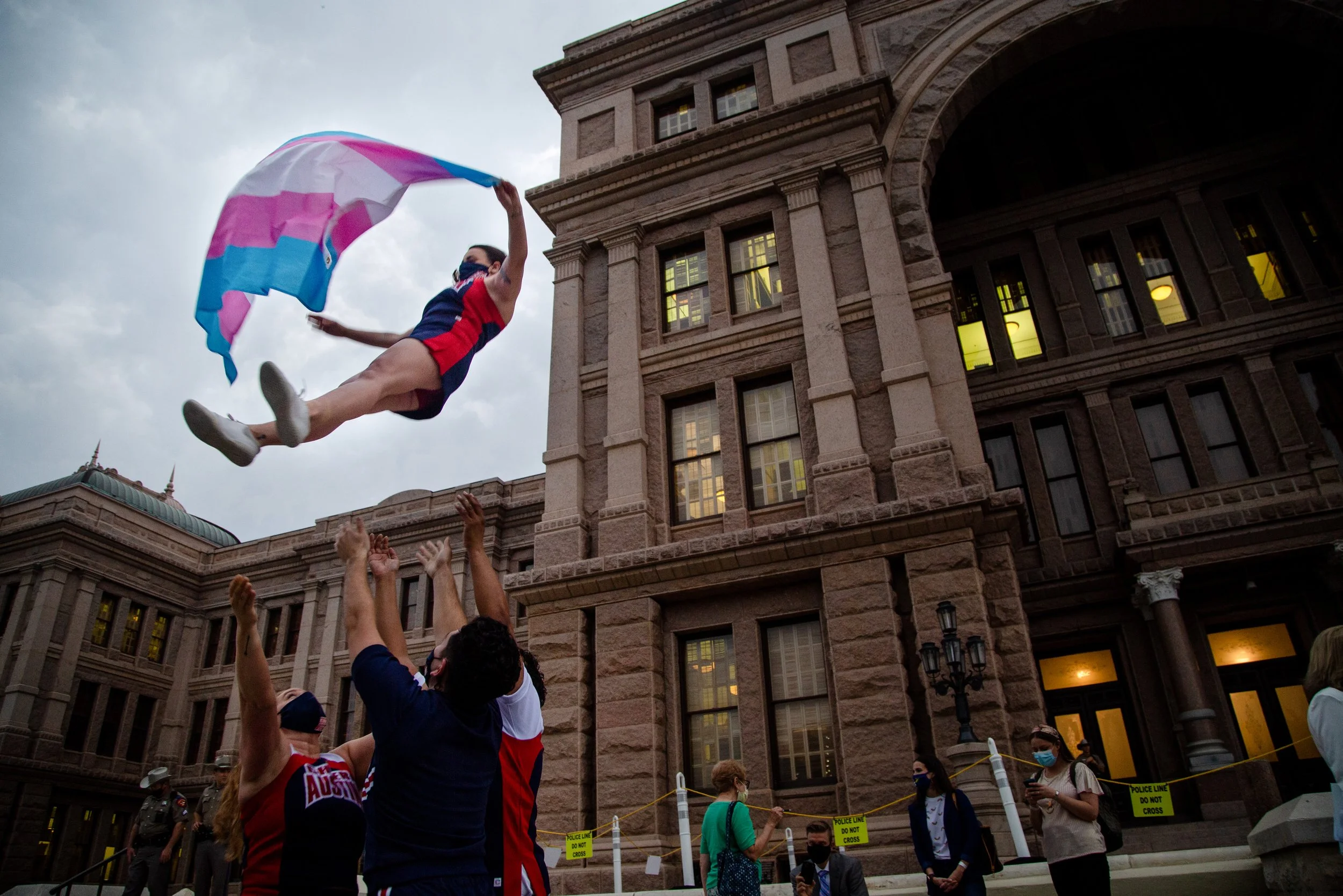  Ali Cross, of the Austin Cheer squad, waves a Trans flag while her squad mates hold her up on the steps of the state capitol at a rally against Anti-Trans legislation on April 28, 2021. 