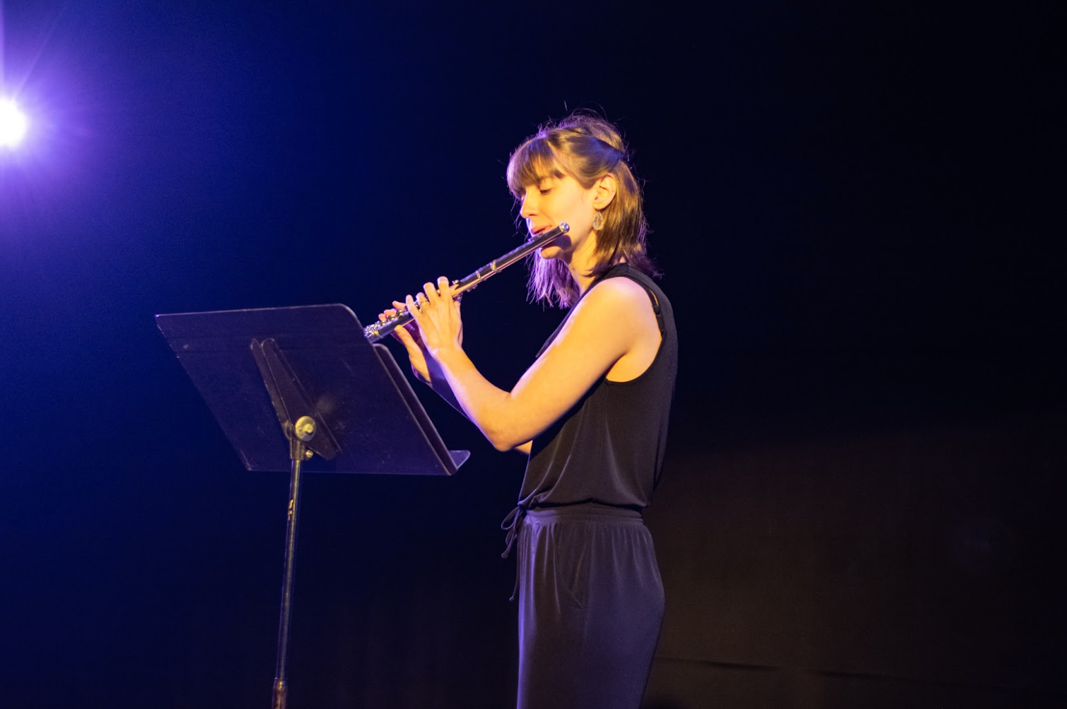 Anne-Marie plays flute on stage in front of a music stand