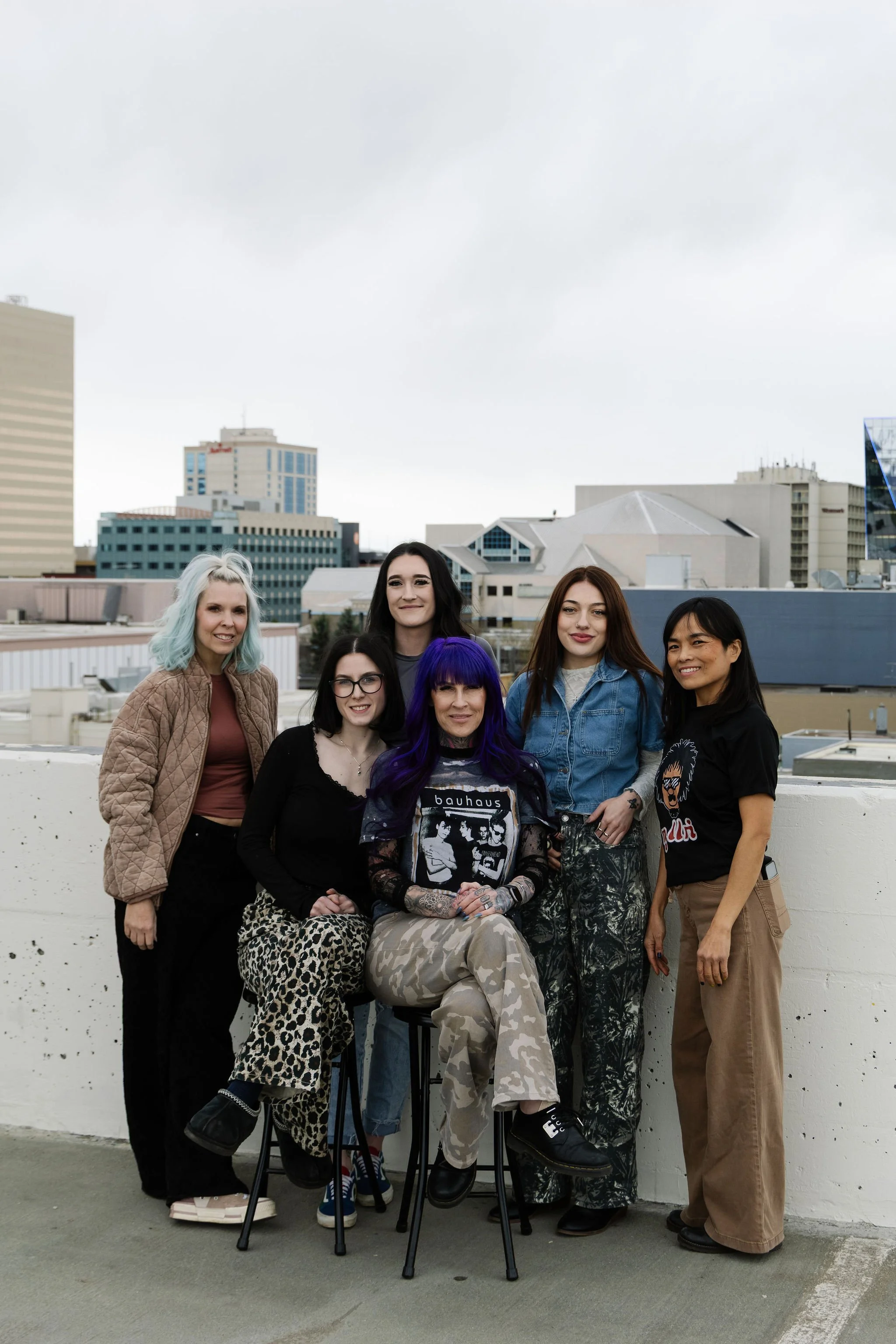 A group of seven diverse  women, offering a full range of salon services including precision haircuts, customized coloring, highlights and balayage, hair extensions, styling for special occasions, treatments for hair health, and personalized consulta